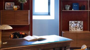 Una sala de estudio con un escritorio, dos sillas, una estantería y una ventana.