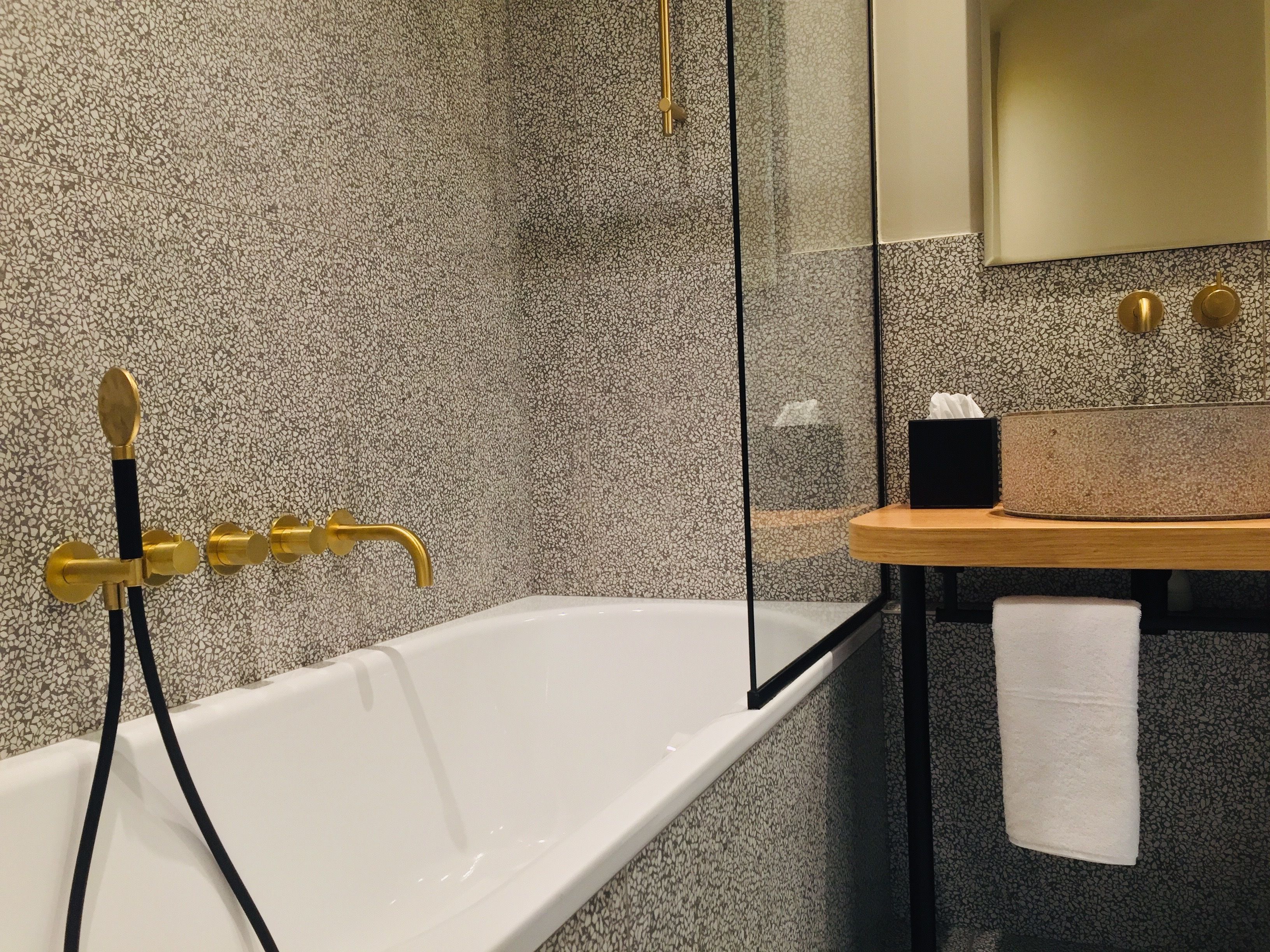 Een moderne badkamer met een vrijstaand bad, een douchecabine met glazen wanden en een houten wastafelmeubel met een handdoek.