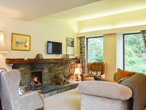 A cozy living room with a stone fireplace, comfortable seating, a flat-screen TV, and a large window with curtains. - 3 bedroom accommodation in Low Newton (Low Newton)