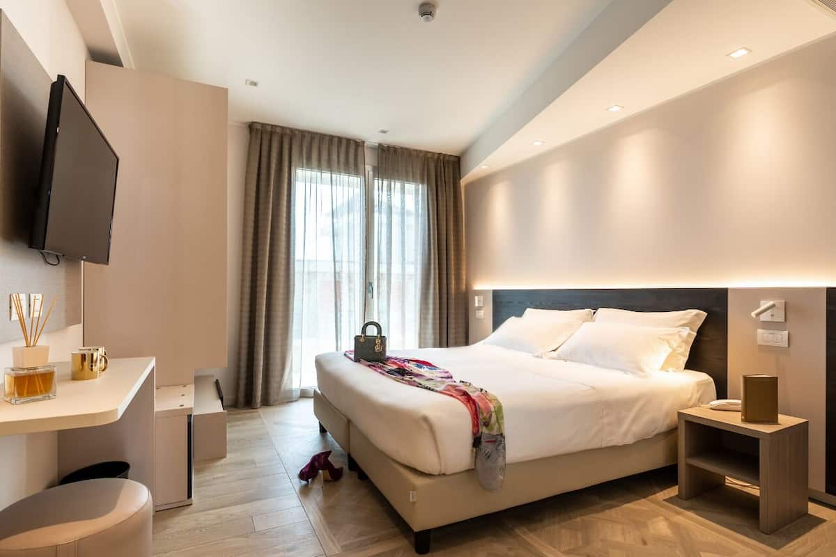 Een moderne hotelkamer met een groot bed, nachtkastjes, een bureau en een televisie.