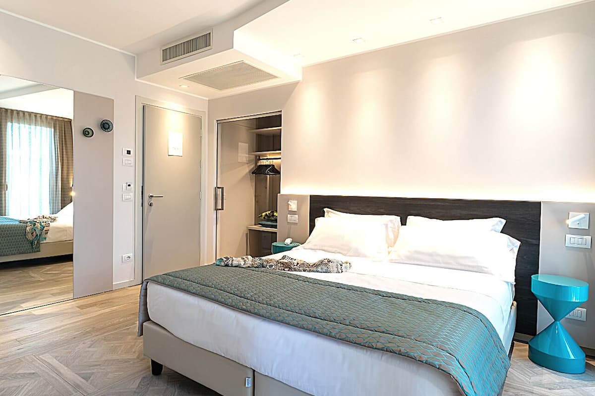 Een moderne hotelkamer met een groot bed, een inloopkast en een badkamer met douche en toilet.