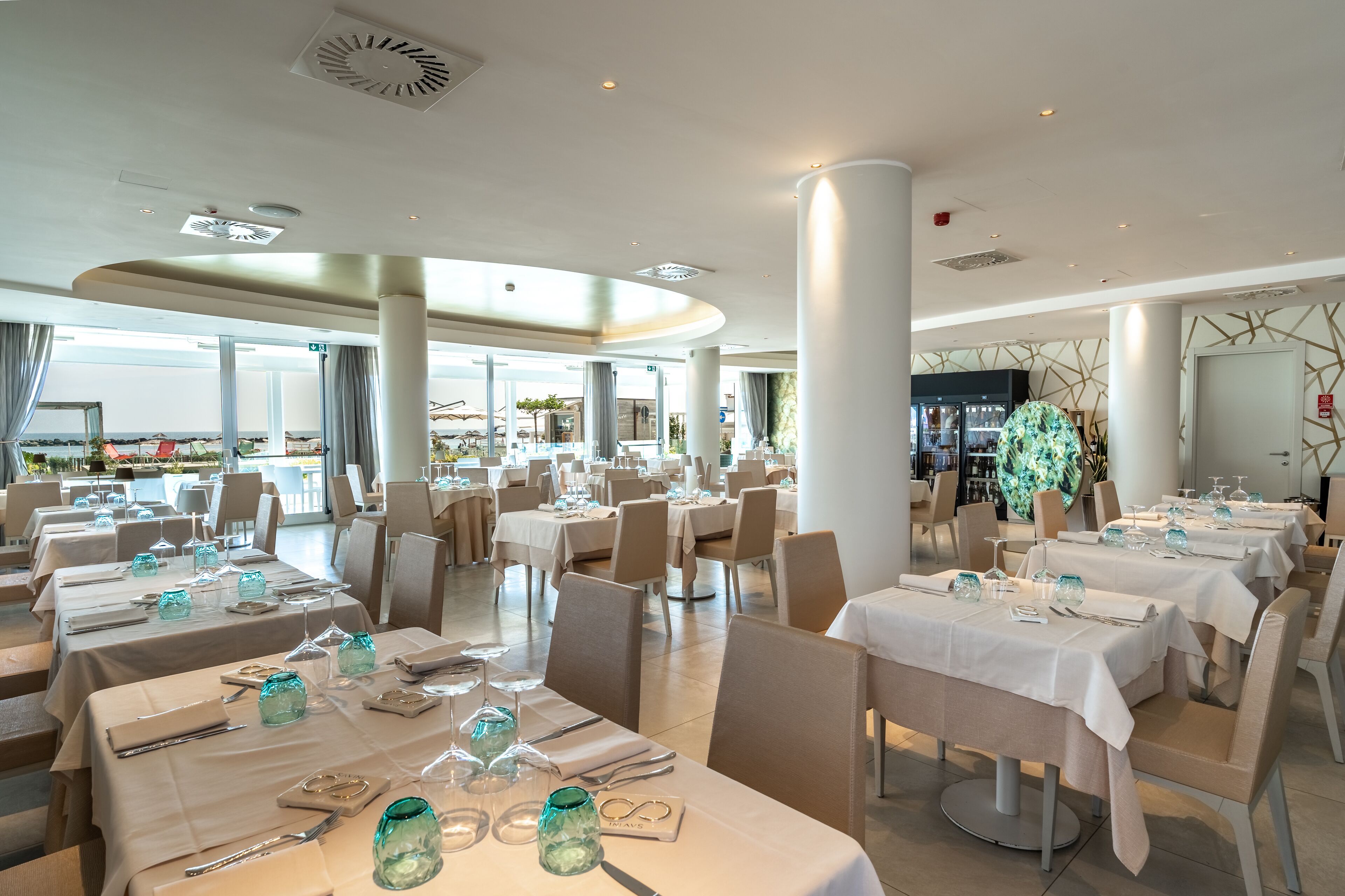 Un restaurant spacieux, doté de nombreuses tables, de grandes fenêtres offrant une vue agréable et d’un décor intérieur moderne.