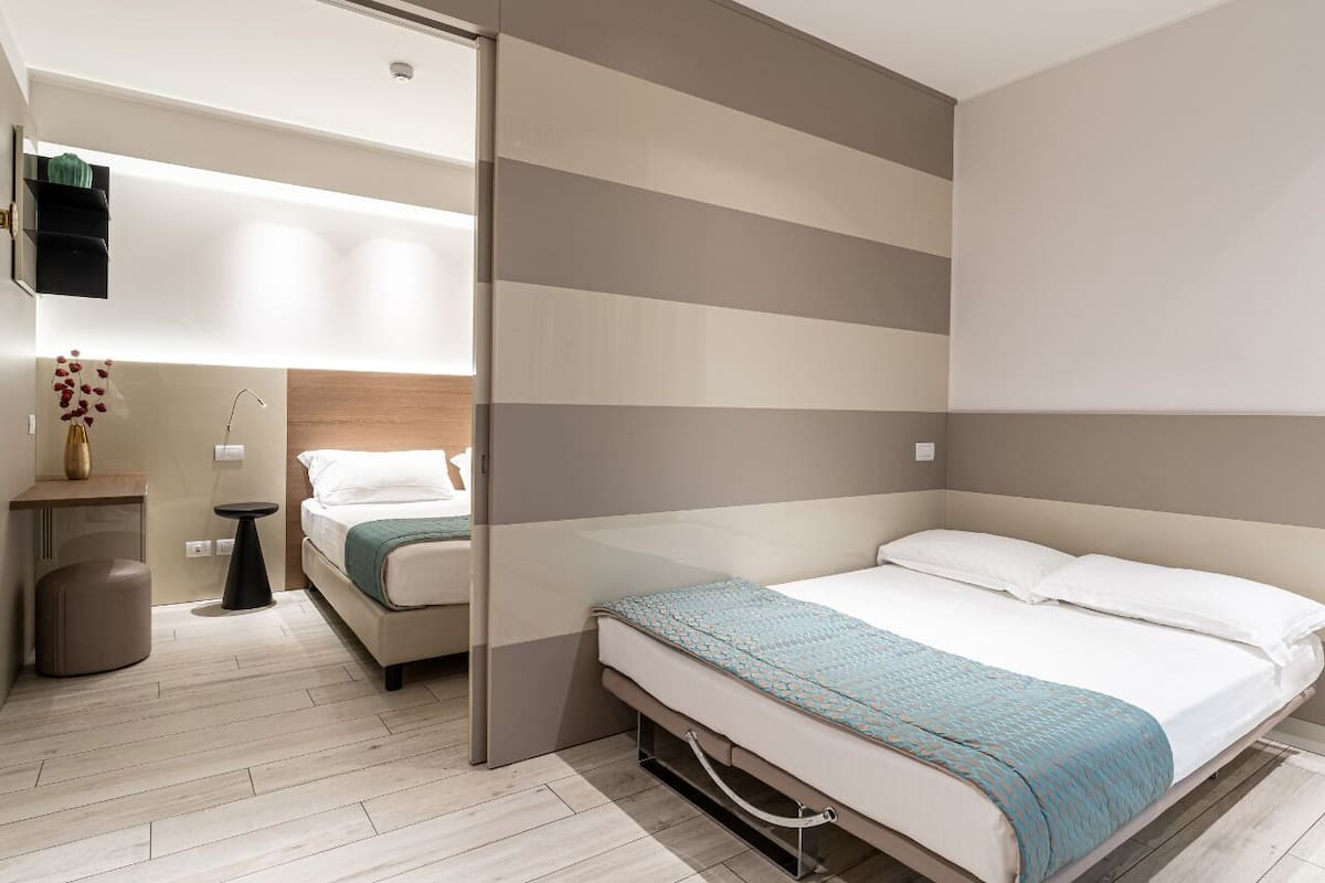 Een moderne slaapkamer met een bed, nachtkastje en een klein krukje.