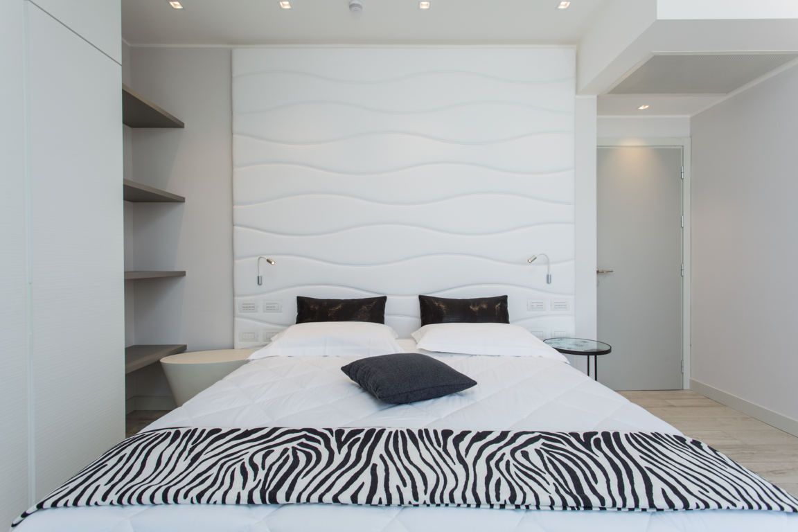 Ein modernes Schlafzimmer mit einem großen Bett, einer Bettdecke mit ZEBRA-Muster und einem einzigartigen, gewellten Kopfteil.