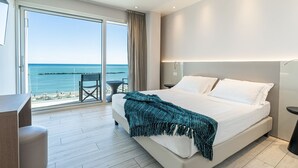 Ein modernes Hotelzimmer mit einem großen Bett, einem Schreibtisch und Meerblick.