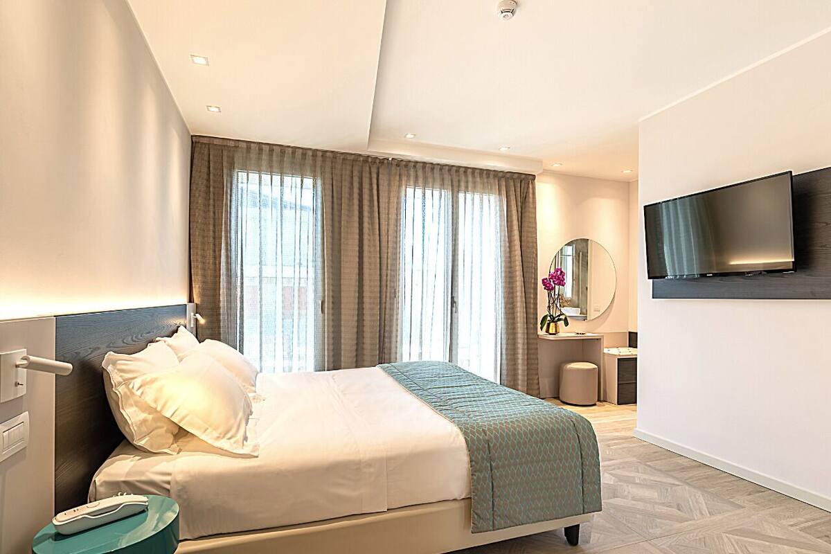 Een moderne hotelkamer met een bed, nachtkastje, televisie en een badgedeelte.
