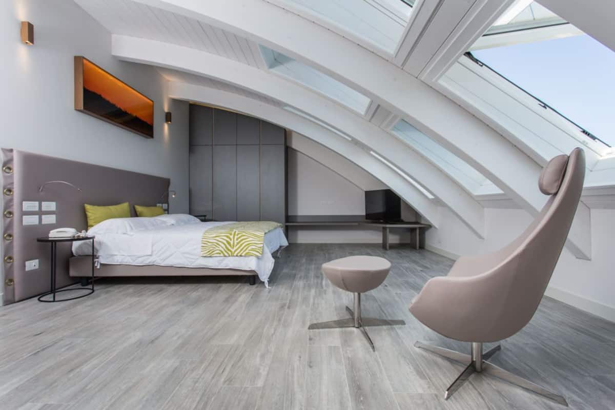 Een moderne slaapkamer met dakraam, een bed met hoofdeinde, een nachtkastje en een stoel.