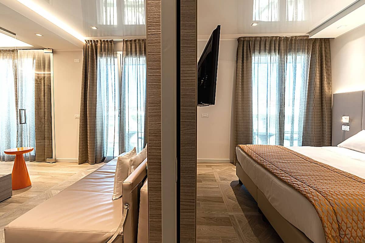 Een moderne hotelkamer met een groot bed, een zithoek met een tafel, en een aan de muur bevestigde televisie.