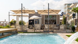 Ein Poolbereich mit Liegestühlen und Sonnenschirmen, einer Bar und einem Wasserfall.