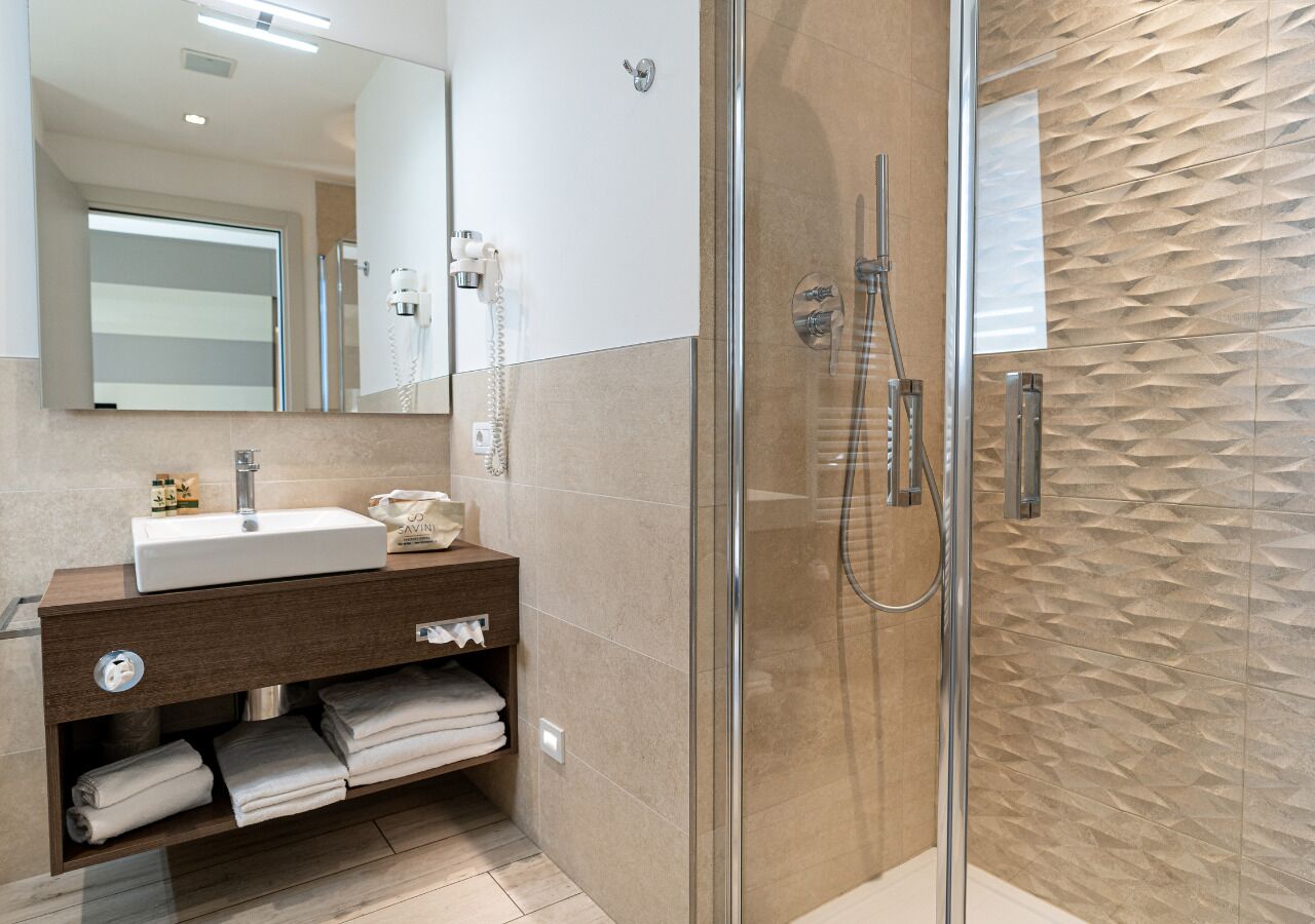 A modern bathroom with a glass-enclosed shower, a white sink, and a wooden vanity.