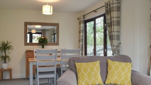 A living room with a sofa, chairs, a dining table, and a potted plant. - 2 bedroom accommodation in Benllech (Benllech)