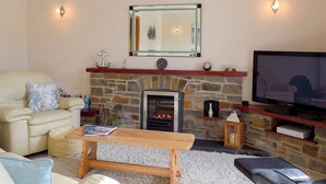 A cozy living room with a stone fireplace, a television, and comfortable seating. - 2 bedroom accommodation in Fishguard (Fishguard)