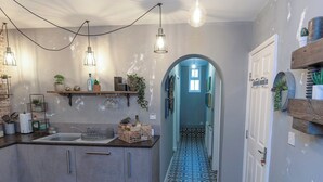 A kitchen with a central island, hanging lights, and a patterned tile floor.