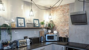 A modern kitchen with a brick wall, stainless steel appliances, and decorative items on the counter.