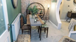 A dining area with a brick wall, a round table with chairs, a radiator, and a bench.