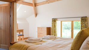 Um quarto com uma cama, cômoda de madeira, escrivaninha e janela com cortinas.