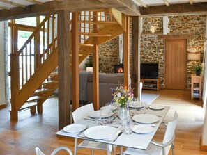 Un coin repas agrémenté d’un escalier en bois, de murs en pierre, d’une cheminée et d’un téléviseur, le tout dans une ambiance chaleureuse.