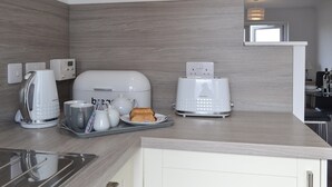 A modern kitchen with a coffee maker, toaster, and a tray with a teapot and cups. - 2 bedroom accommodation in Oban (Oban)