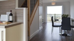 A modern kitchen with a wooden staircase, a dining area with a table and chairs, and a view of the outdoors. - 2 bedroom accommodation in Oban (Oban)