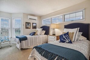 A bedroom with two beds, a nightstand, a lamp, and a chair. - Fabulous Find - Spendlove Oceanfront (Duck)