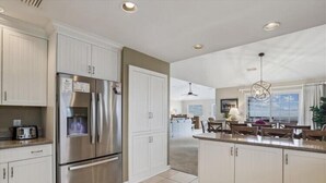 A modern kitchen with stainless steel appliances, white cabinetry, and a central island. - Fabulous Find - Spendlove Oceanfront (Duck)
