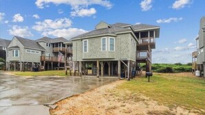 A waterfront property with multiple two-story houses, a covered walkway, and a flag. - Fabulous Find - Spendlove Oceanfront (Duck)
