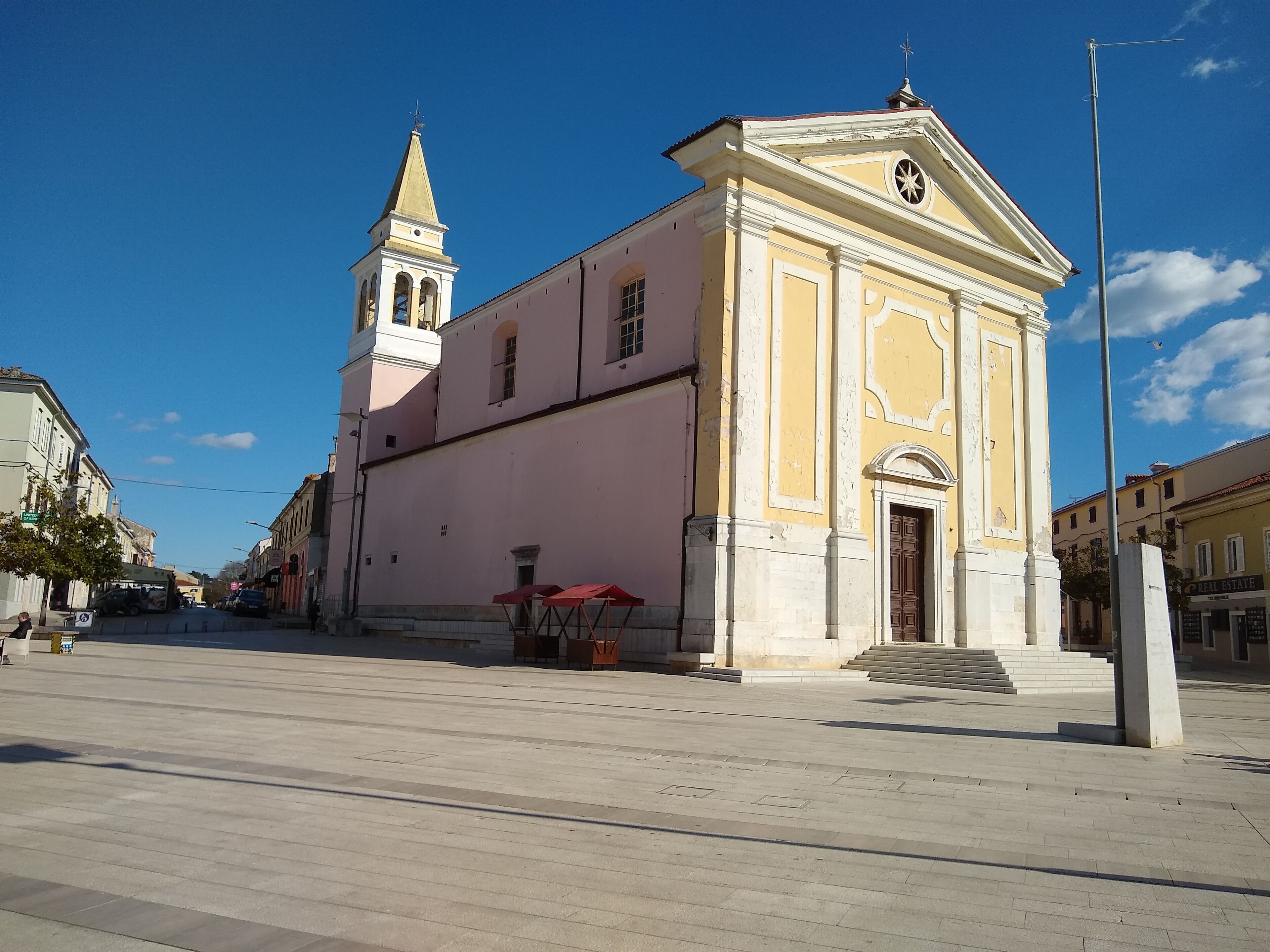 A church with a bell tower and a large open plaza in front.