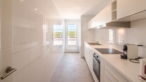 A modern kitchen with white cabinetry, a stainless steel sink, and a built-in oven.