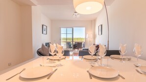 A dining area with a large table set for six, equipped with plates, cutlery, and wine glasses.