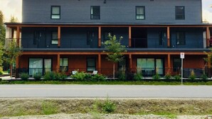 A two-story building with a flat roof, large windows, and a balcony on the ground floor. - Perfect for your Winter and Summer Vacations! (Revelstoke)