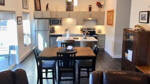 A modern kitchen with a dining area, featuring a central island, wooden cabinets, and a built-in microwave. - Perfect for your Winter and Summer Vacations! (Revelstoke)