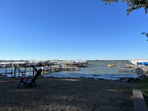 A beach with a chair and a dock with boats.