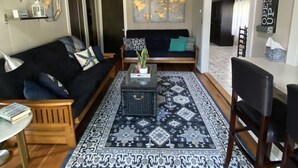 Ein Wohnzimmer mit einem dunkelgrauen Sofa, einem Couchtisch und einem gemusterten Teppich.