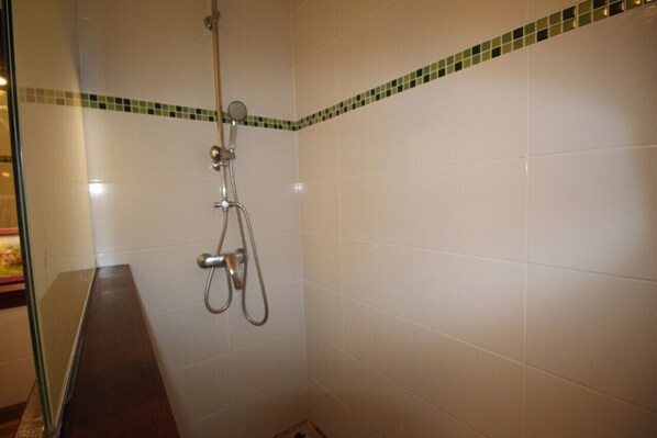 Un pequeño espacio de ducha con azulejos, un cabezal de ducha de mano y un grifo instalado en la pared.