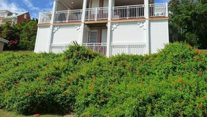 A two-story building with a balcony on the upper floor, surrounded by dense green shrubbery. - Nice furnished studio with small sea view<br><br><br> (SAINT FRANCOIS)