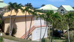 A residential building with a green roof, a staircase, and palm trees. - Nice furnished studio with small sea view<br><br><br> (SAINT FRANCOIS)