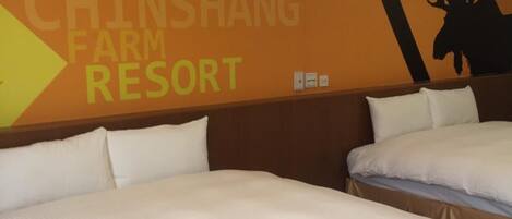 Una habitación de hotel con dos camas, una pared con un cartel grande que dice "TORAL CHINSHANG FARM RESORT" y la silueta de un alce.