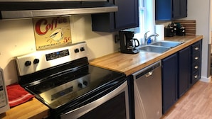 A kitchen with dark cabinets, a stainless steel stove, a coffee maker, and a dishwasher. - Best Location on the MIssouri River (Cascade)