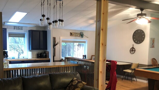 A living room with a dark leather sofa, a wooden coffee table, a pool table, and a kitchen area in the background. - Best Location on the MIssouri River (Cascade)