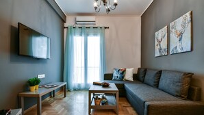 Una sala de estar moderna con un televisor de pantalla plana, un sofá, una mesa de centro y un banco.