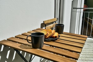 A wooden table with two black mugs and a plate of food on a balcony. - Domino 1 (Kallithea)