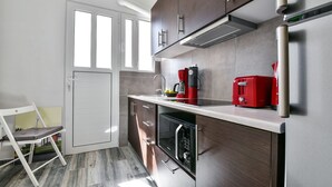Una cocina moderna con armarios de madera oscura, encimera de acero inoxidable, horno integrado y una cafetera roja.