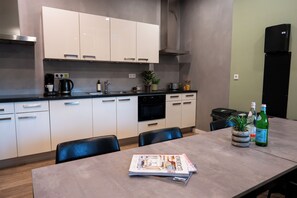 A modern kitchen with white cabinets, a black countertop, and a dining area with a table and chairs.