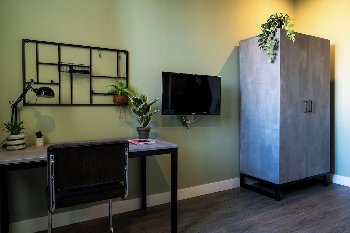 Une pièce comprenant un bureau, une chaise, un téléviseur et un meuble.