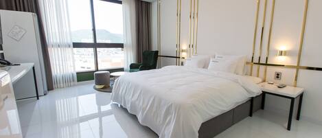 Habitación de hotel moderna con una cama grande, un escritorio, una silla y vistas a la ciudad.