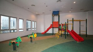 A children's play area with a slide, climbing structures, and a small green motorcycle toy. - OYO Home 580 Luxury 2 Bedroom Taragon Puteri (Kuala Lumpur)