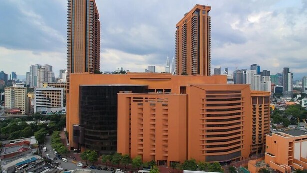 A high-rise building with a modern design, featuring a prominent central tower and two smaller towers on either side. - OYO Home 580 Luxury 2 Bedroom Taragon Puteri (Kuala Lumpur)
