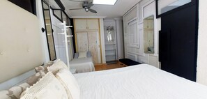 A bedroom with a bed, a wardrobe, a mirror, and a ceiling fan.