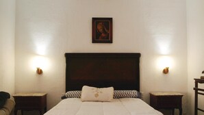 Ein Hotelzimmer mit einem großen Bett, zwei Nachttischen, einer Kopfteil und zwei Wandleuchten.
