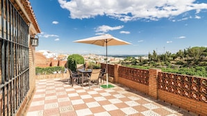 Eine Terrasse mit Schachbrettboden, einem Tisch mit Stühlen und einem Sonnenschirm.